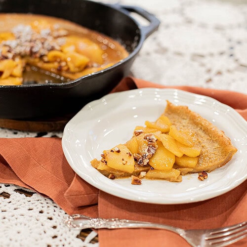 slice of sourdough apple dutch baby pancake with caramelized apples on plate