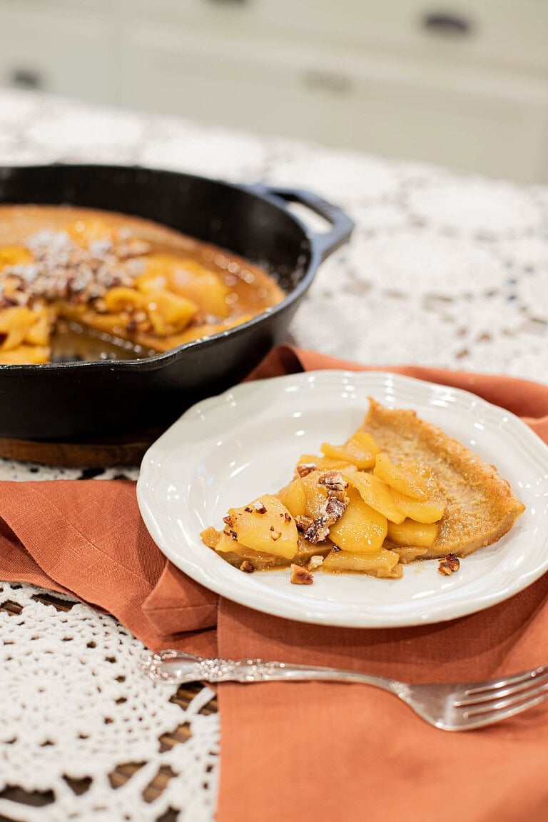 slice of sourdough apple dutch baby pancake with caramelized apples on plate