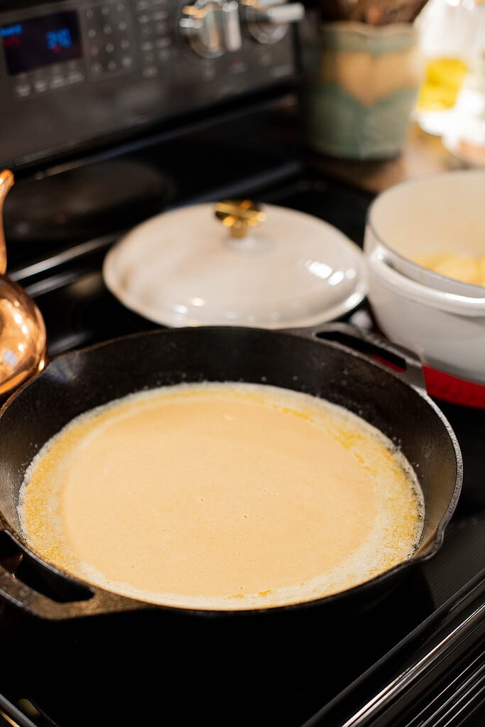 sourdough dutch baby pancake batter cooking in cast iron pan