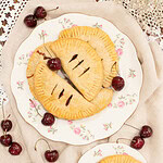 Homemade cherry hand pies with flaky crust served with fresh cherries and cherry jam