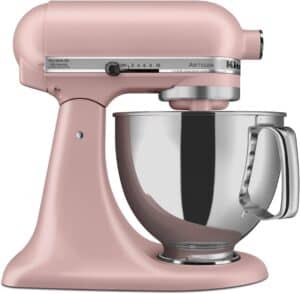 A pink KitchenAid Artisan stand mixer with a stainless steel mixing bowl, featuring multiple speed settings and a tilt-head design for easy access.