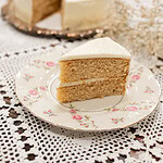 Slice of sourdough vanilla cake made with fresh milled flour on a floral vintage plate with white buttercream frosting and layered crumb visible.