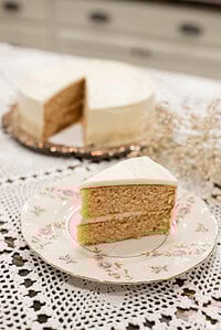 Slice of sourdough vanilla cake made with fresh milled flour on a floral vintage plate with white buttercream frosting and layered crumb visible.
