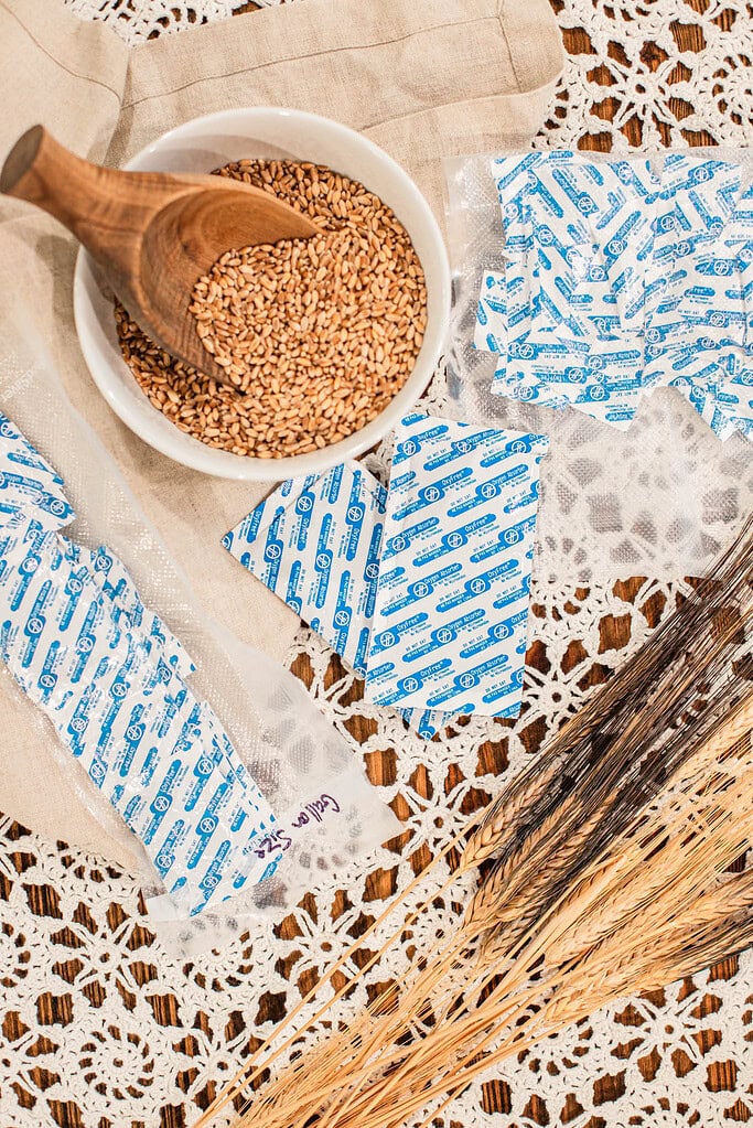 Oxygen absorbers and wheat berries with scoop on lace tablecloth for long term storage prep