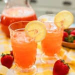 Close-up of two glasses filled with vibrant strawberry lemonade and lemon slices on the rim, ready to be enjoyed on a summer day.