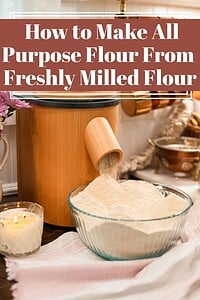 Freshly milled flour pouring from a wooden grain mill into a glass bowl on a cozy kitchen counter, with soft lighting, a candle, and text overlay reading “How to Make All Purpose Flour From Freshly Milled Flour”
