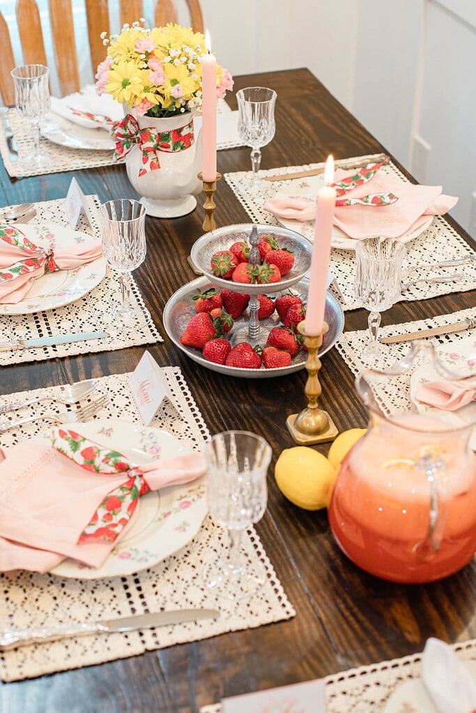 Strawberries on tiered tray with pink candles and lemonade pitcher on cottage dining table