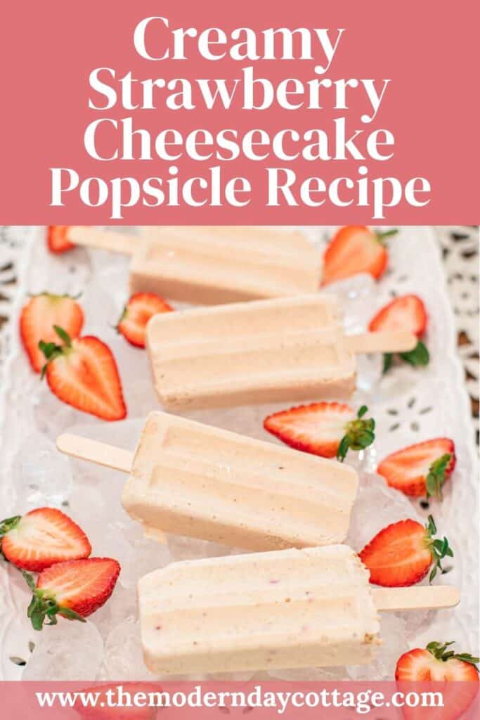 Pinterest graphic featuring a tray of creamy strawberry cheesecake popsicles on ice with sliced strawberries, overlaid with the text “Creamy Strawberry Cheesecake Popsicle Recipe” and the website URL www.themoderndaycottage.com.