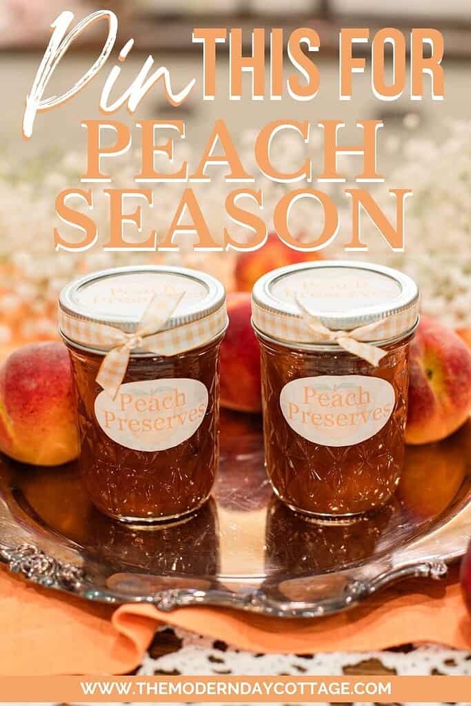 Two jars of homemade peach preserves with gingham ribbon and peach-shaped labels sit on a vintage silver tray, surrounded by fresh peaches and baby’s breath flowers, with text overlay that reads ‘Pin This for Peach Season’ and a website link: www.themoderndaycottage.com.