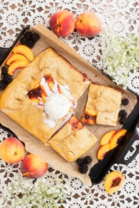 Sourdough peach blackberry galette with fresh milled flour topped with vanilla ice cream on baking tray