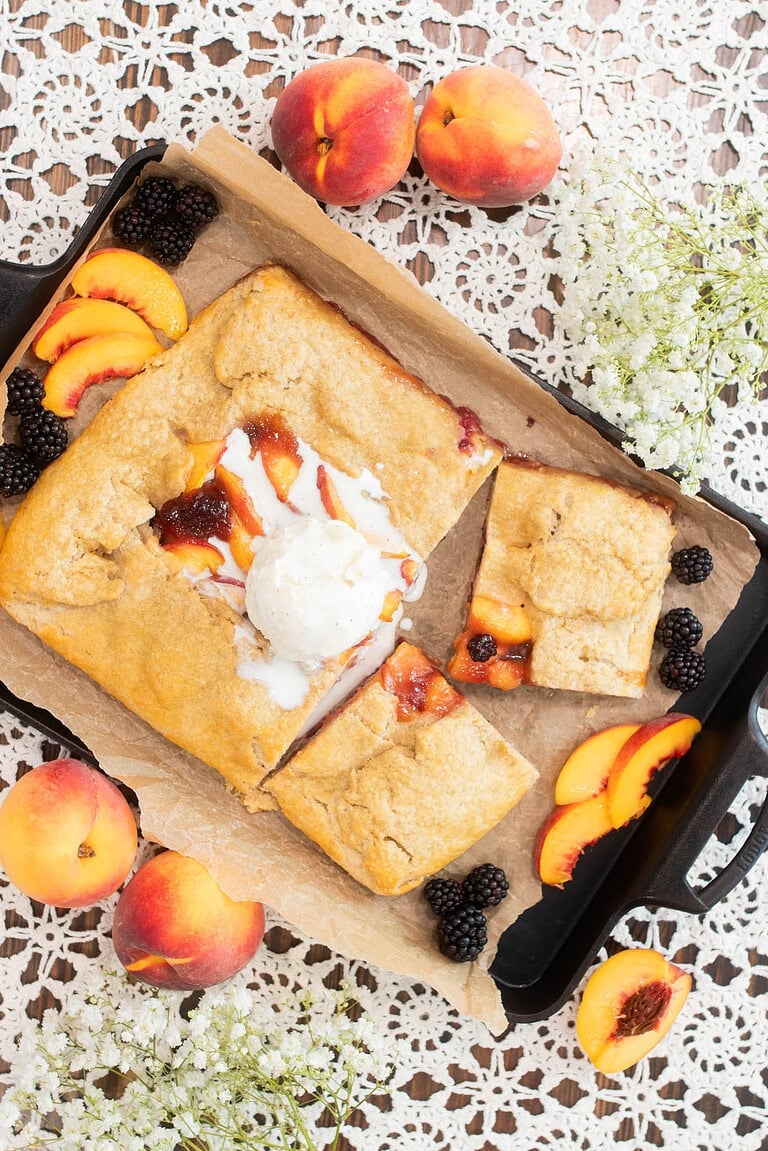 Sourdough peach blackberry galette with fresh milled flour topped with vanilla ice cream on baking tray