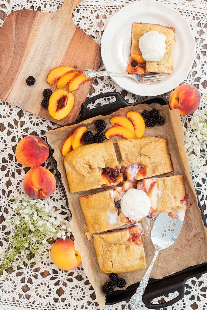 Overhead sourdough peach blackberry galette with sliced peaches, blackberries, and plated serving