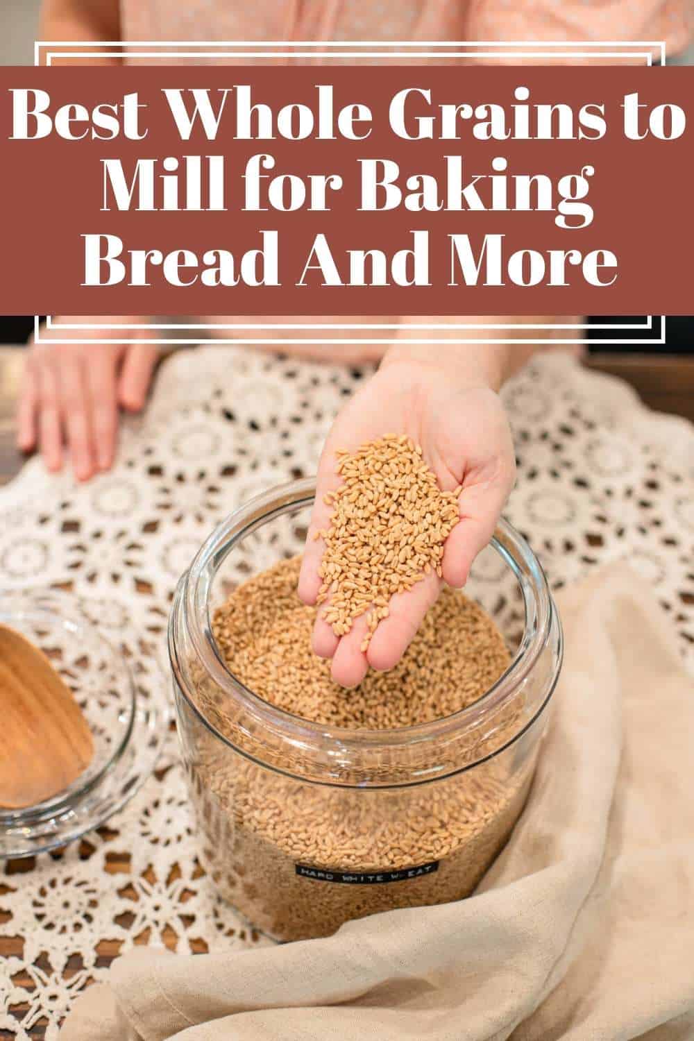 Hands scooping wheat berries from a glass storage jar.