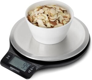 Digital kitchen scale with a bowl of sliced almonds on top, displaying the weight on the LCD screen.