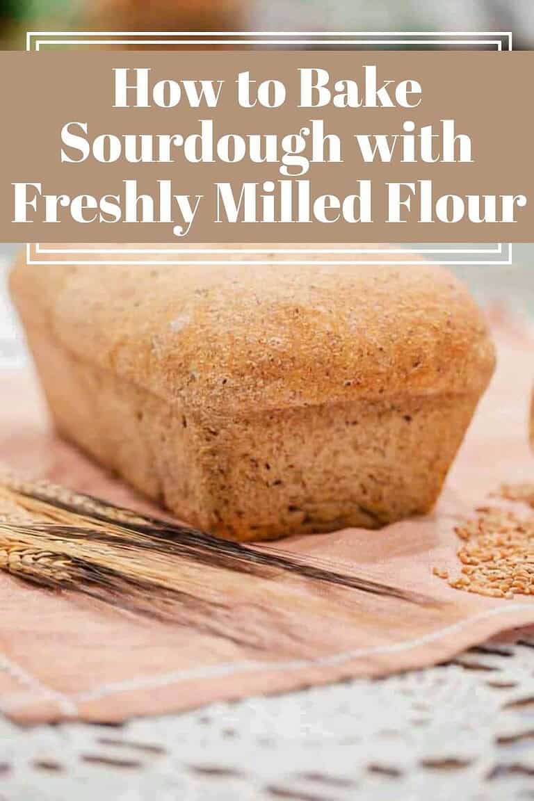 Loaf of homemade bread on a pink cloth with wheat stalks and text overlay reading how to bake sourdough with freshly milled flour.