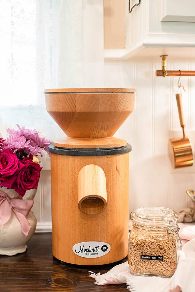A wooden flour mill with a wide wooden hopper on top.