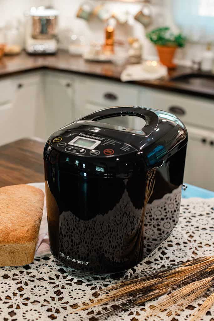 Black bread machine on kitchen counter for home baking.