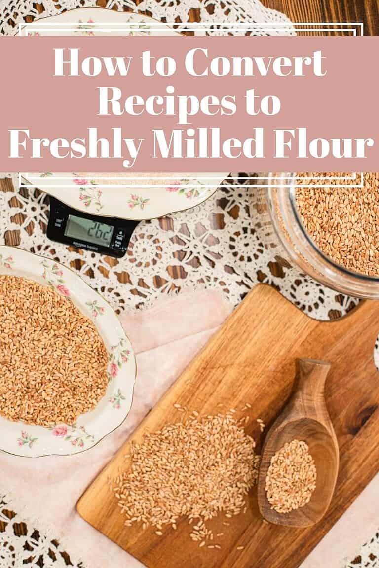 Vintage cottage kitchen scene with bowls of wheat berries and freshly ground flour on lace doilies and wooden boards, showing how to convert recipes for freshly milled flour.