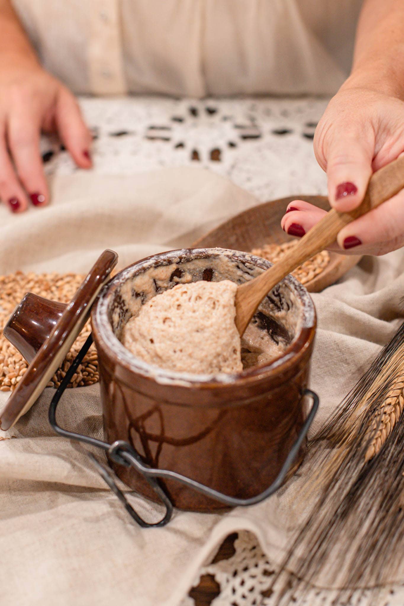 Mixing freshly milled flour sourdough starter by hand with whole wheat berries in the background