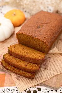 Pumpkin bread made with freshly milled flour, sliced into thick pieces showing a soft, moist crumb, with text overlay reading “Pumpkin Bread with Freshly Milled Flour.”