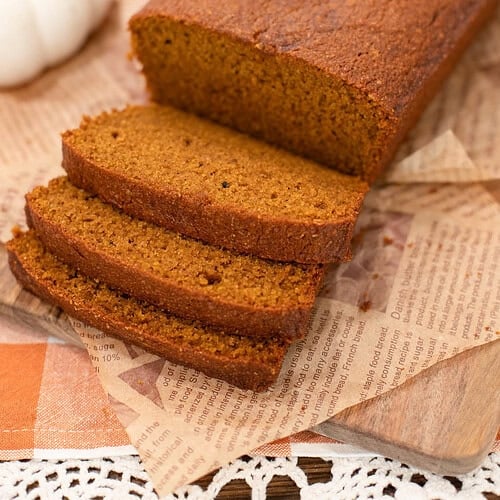 Pumpkin bread made with freshly milled flour, sliced into thick pieces showing a soft, moist crumb, with text overlay reading “Pumpkin Bread with Freshly Milled Flour.”