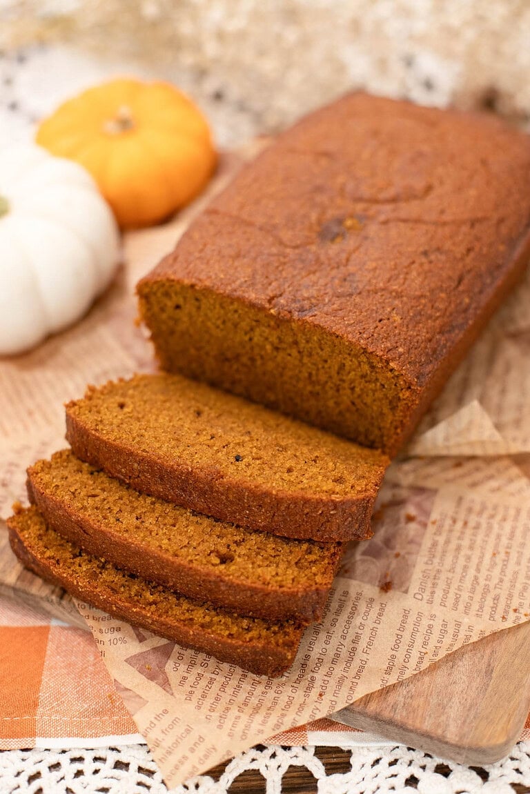 Pumpkin bread made with freshly milled flour, sliced into thick pieces showing a soft, moist crumb, with text overlay reading “Pumpkin Bread with Freshly Milled Flour.”