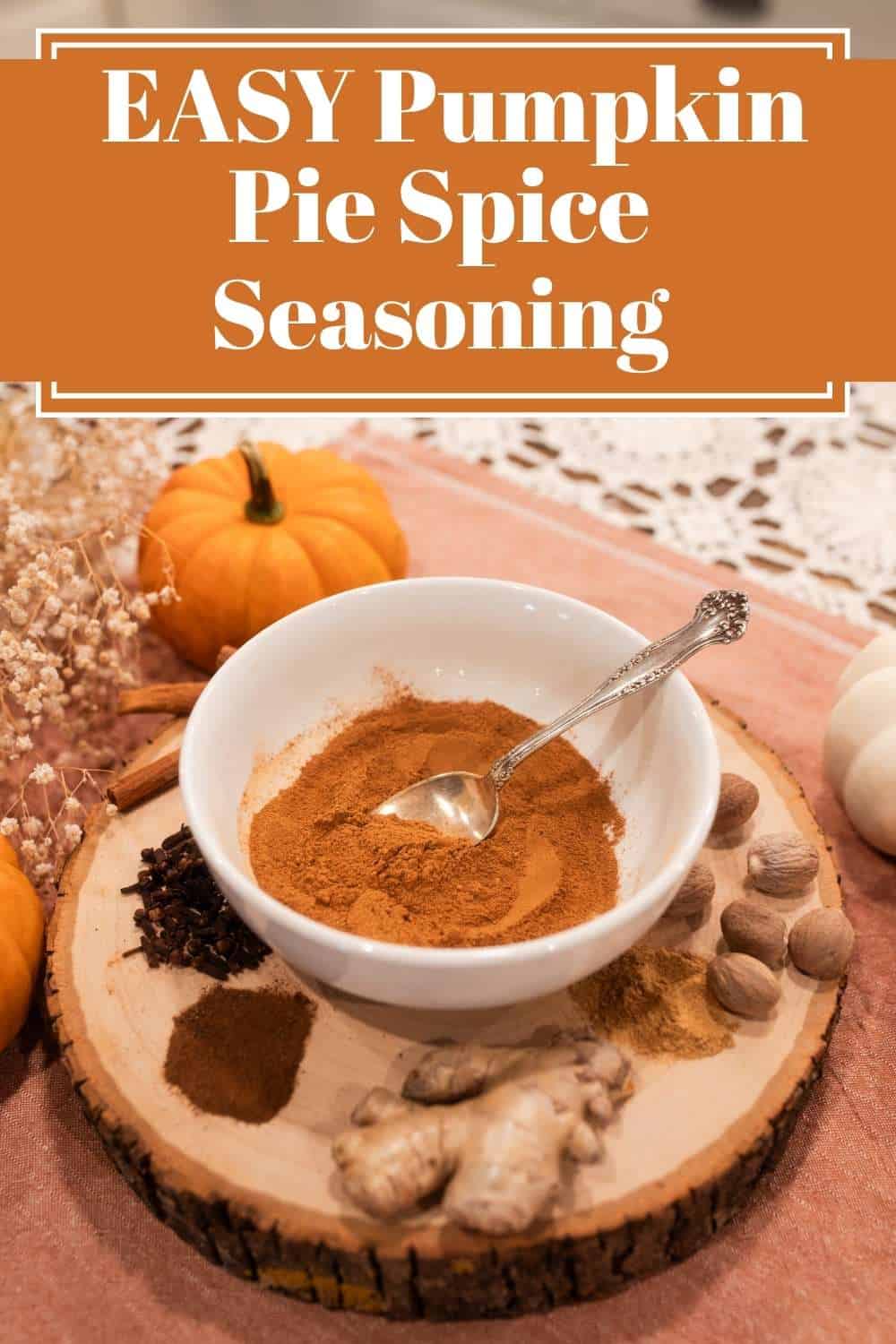 A cozy autumn scene featuring a white bowl filled with pumpkin pie spice on a rustic wooden board, surrounded by whole nutmeg, cloves, cinnamon sticks, fresh ginger, and small pumpkins, with the text “Easy Pumpkin Pie Spice Seasoning” displayed above.
