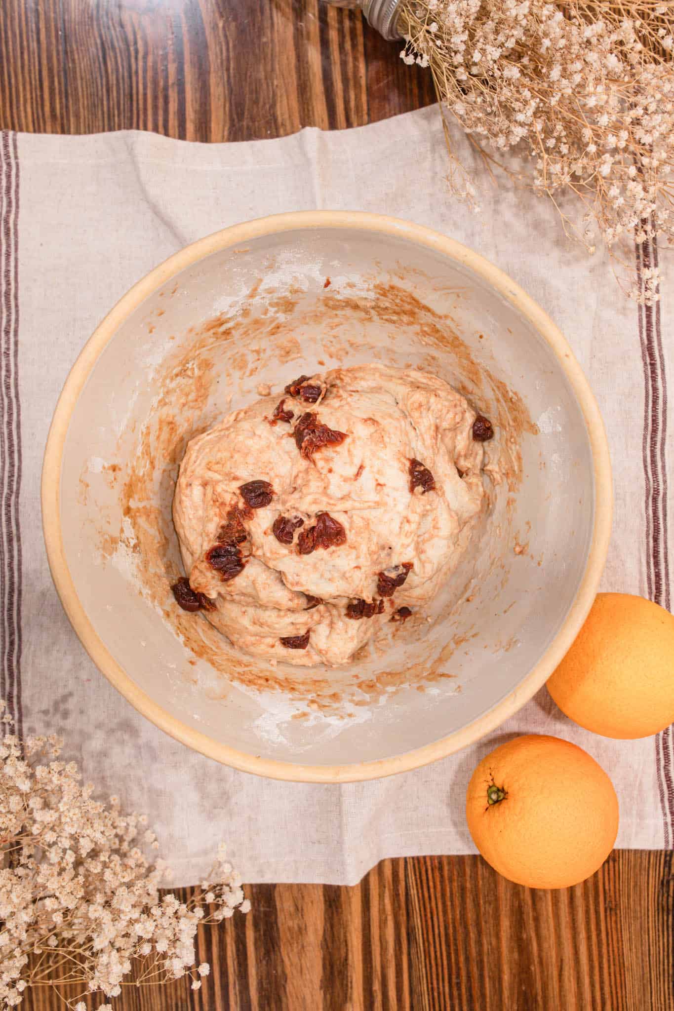 Bowl of sourdough cranberry orange bread dough after mixing, showing bits of dried cranberries and a soft, sticky texture.