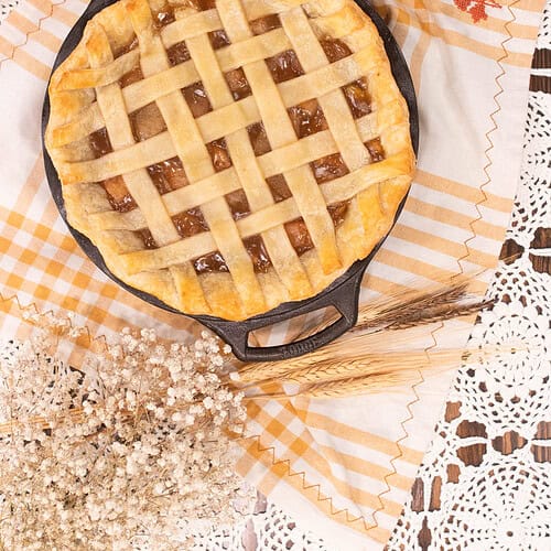Golden brown lattice-top pie baked in a cast iron skillet with a flaky homemade pie crust.