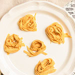 Freshly cut sourdough einkorn pasta nests on a white serving plate.