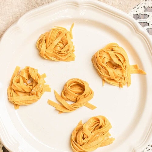 Freshly cut sourdough einkorn pasta nests on a white serving plate.
