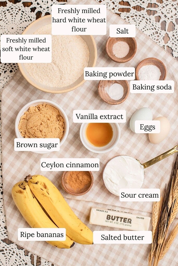 Labeled ingredients for banana muffins with freshly milled flour, including freshly milled soft and hard white wheat flour, ripe bananas, brown sugar, sour cream, eggs, and Ceylon cinnamon