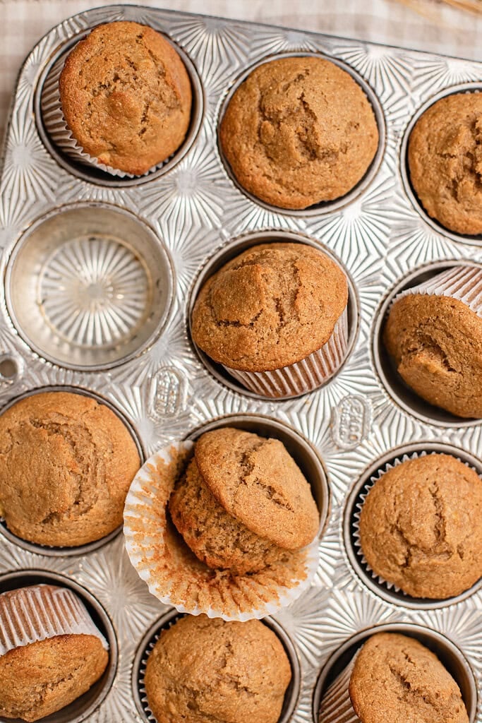 Close up of a fresh milled flour banana muffin with wrapper peeled back to show a moist crumb