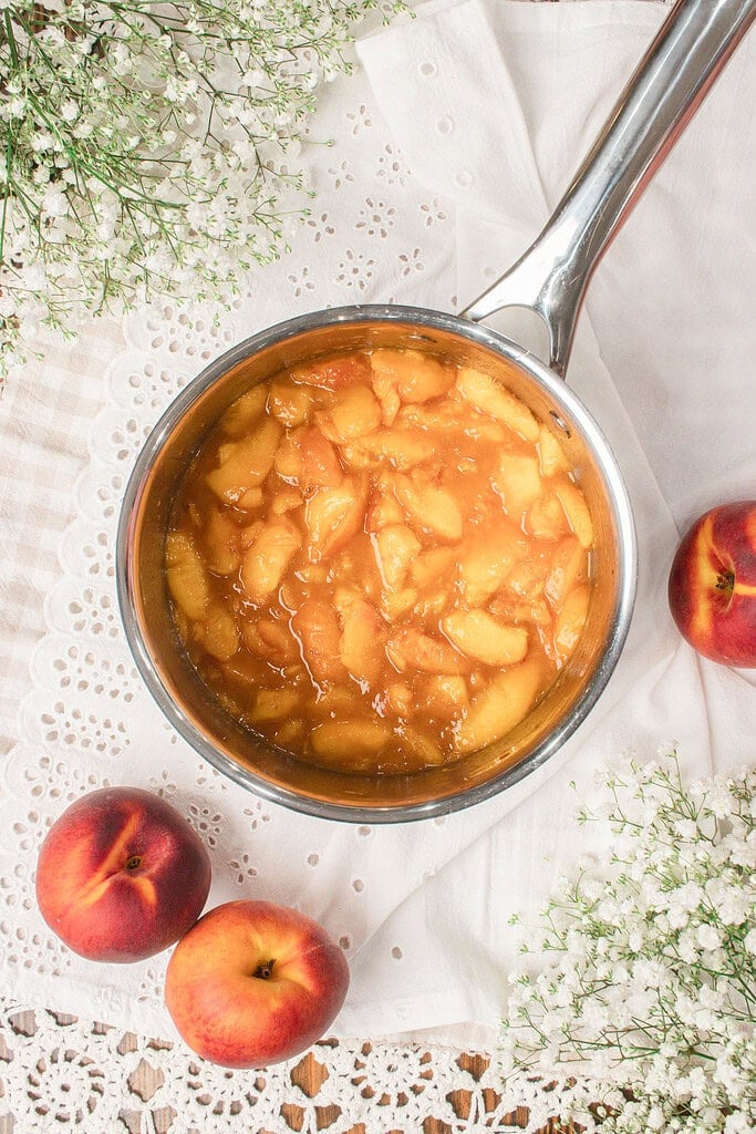 Fresh peach filling cooking in a saucepan with cinnamon for brown butter peach custard ice cream