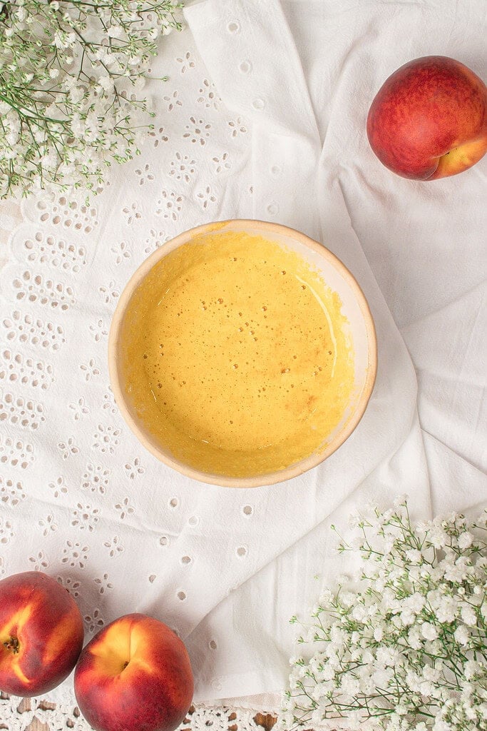 Overhead view of brown butter and egg yolk mixture in a bowl for custard ice cream base