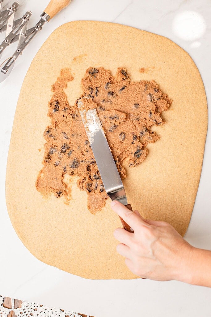 Spreading cinnamon raisin filling over rolled out freshly milled flour dough