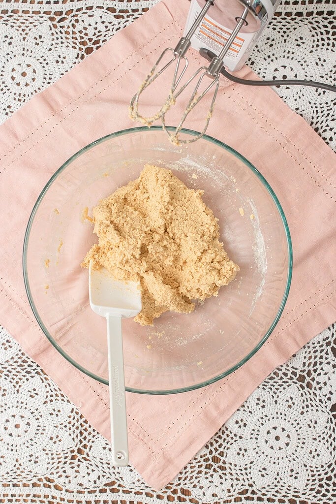 hly mixed cookie dough for the fruit pizza crust in a glass bowl with a hand mixer and spatula resting nearby