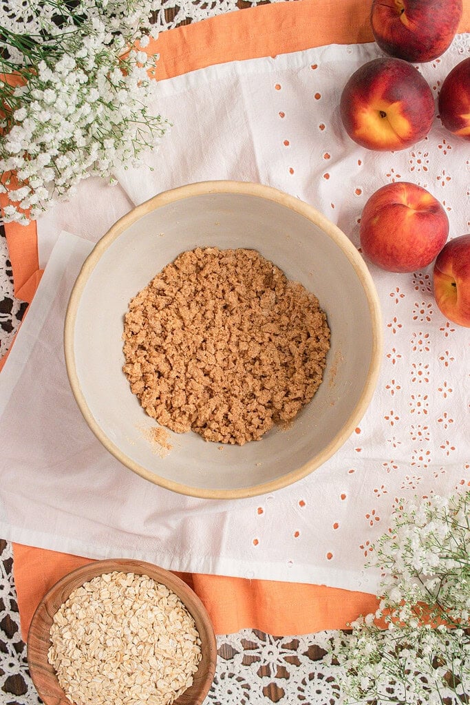 Fresh milled flour peach crisp topping mixed together before adding rolled oats for a homemade peach crisp recipe.