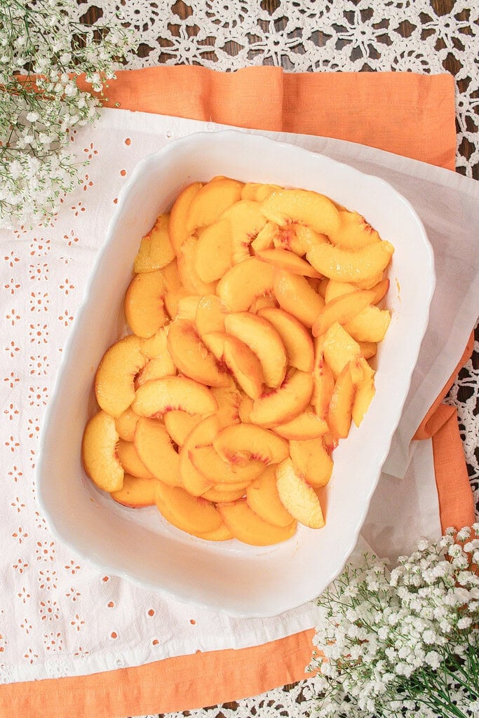 Fresh sliced peaches arranged in a baking dish before adding the fresh milled flour oat crisp topping for homemade peach crisp.