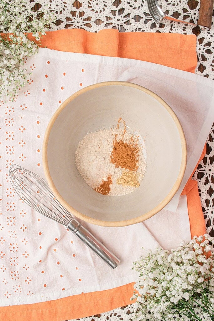 Dry ingredients for fresh milled flour peach crumble topping including freshly milled flour, brown sugar, cinnamon, ginger, baking powder, and salt in a mixing bowl.