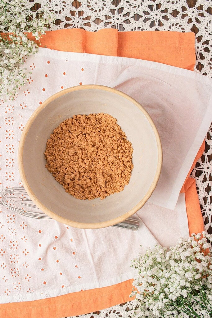 Fresh milled flour crumble topping mixed together in a bowl before sprinkling over homemade peach crumble.
