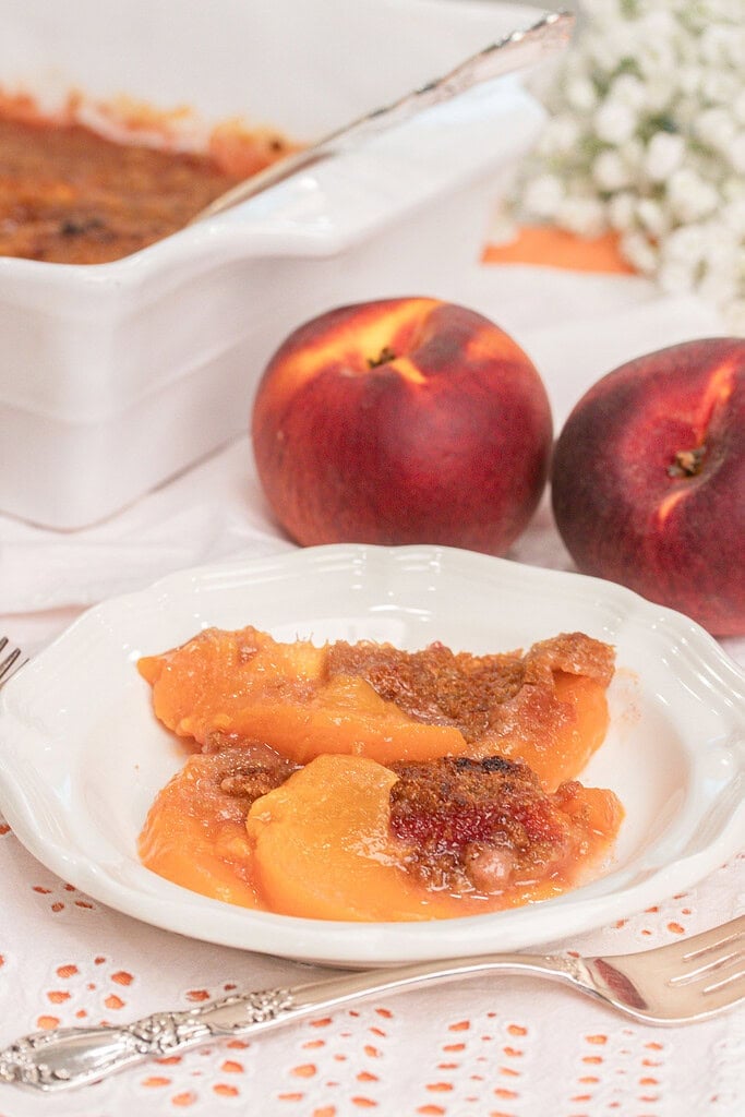 Serving of homemade peach crumble with fresh milled flour in a white dessert bowl featuring tender baked peaches and a golden cinnamon crumble topping.