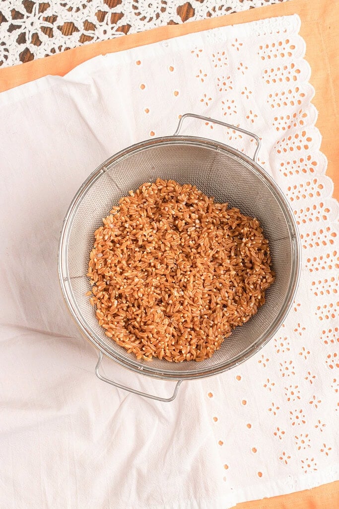 Cooked farro draining in a fine mesh strainer after cooking for homemade peach farro salad.