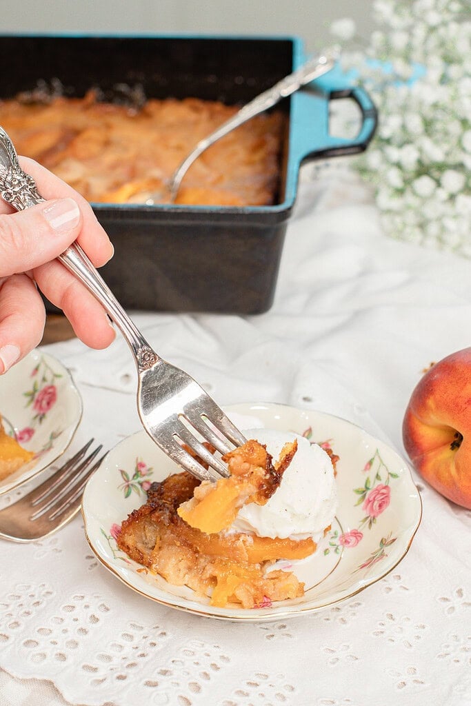 Delicious sourdough peach cobbler served with ice cream on a vintage plate.