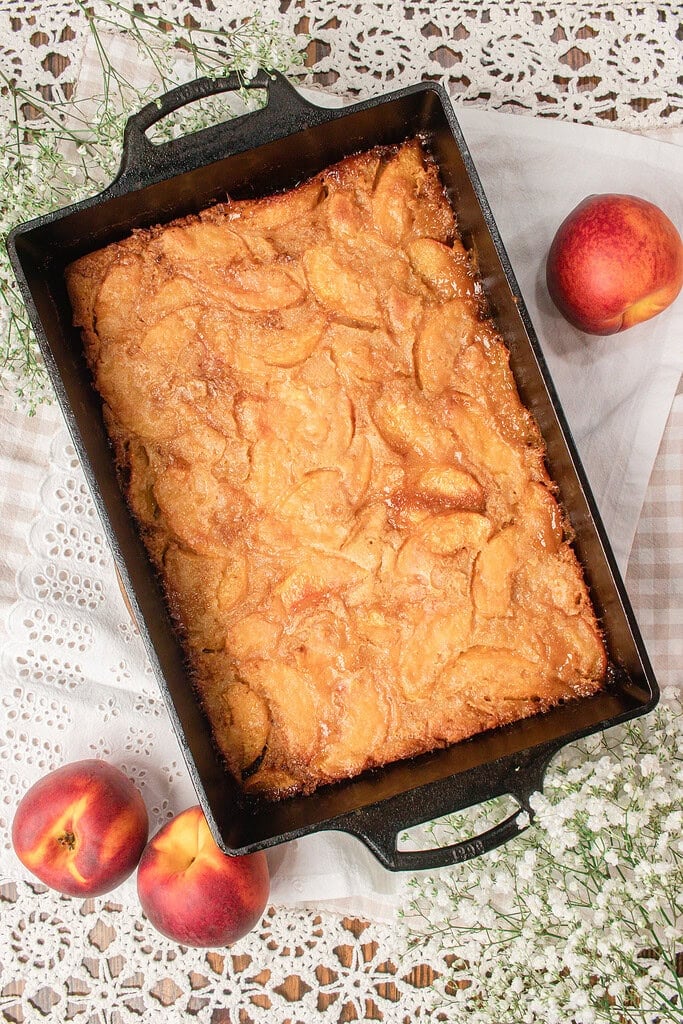 Freshly baked sourdough peach cobbler with fresh milled flour golden brown in a cast iron baking dish, ready to serve.
