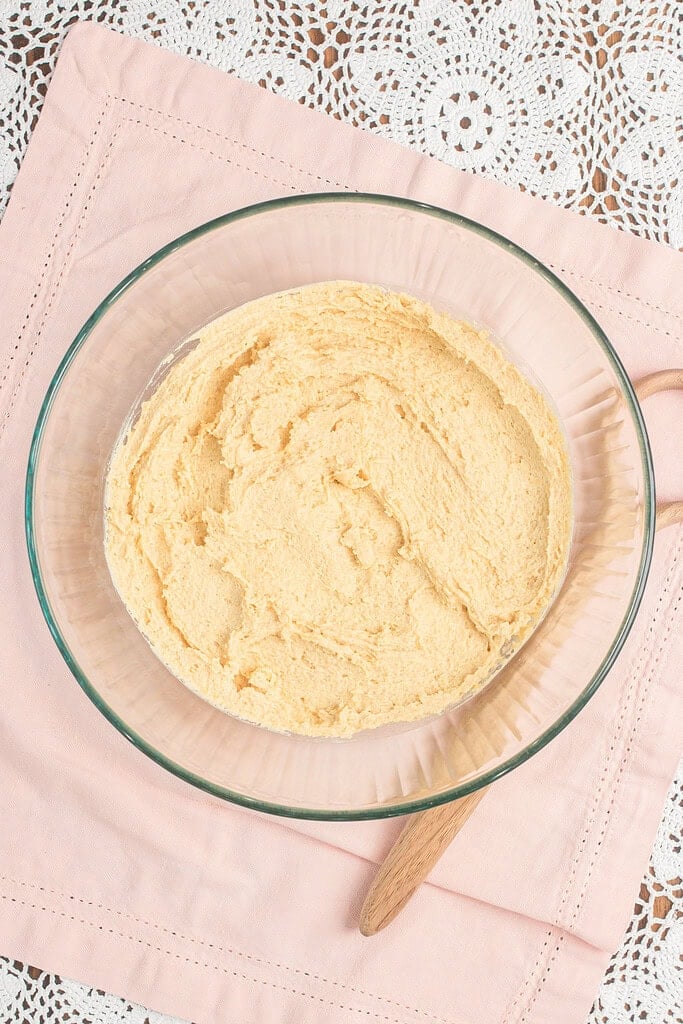 Creamed butter and sugar in a glass mixing bowl with a wooden spoon resting against the side, ready for the wet ingredients to be added