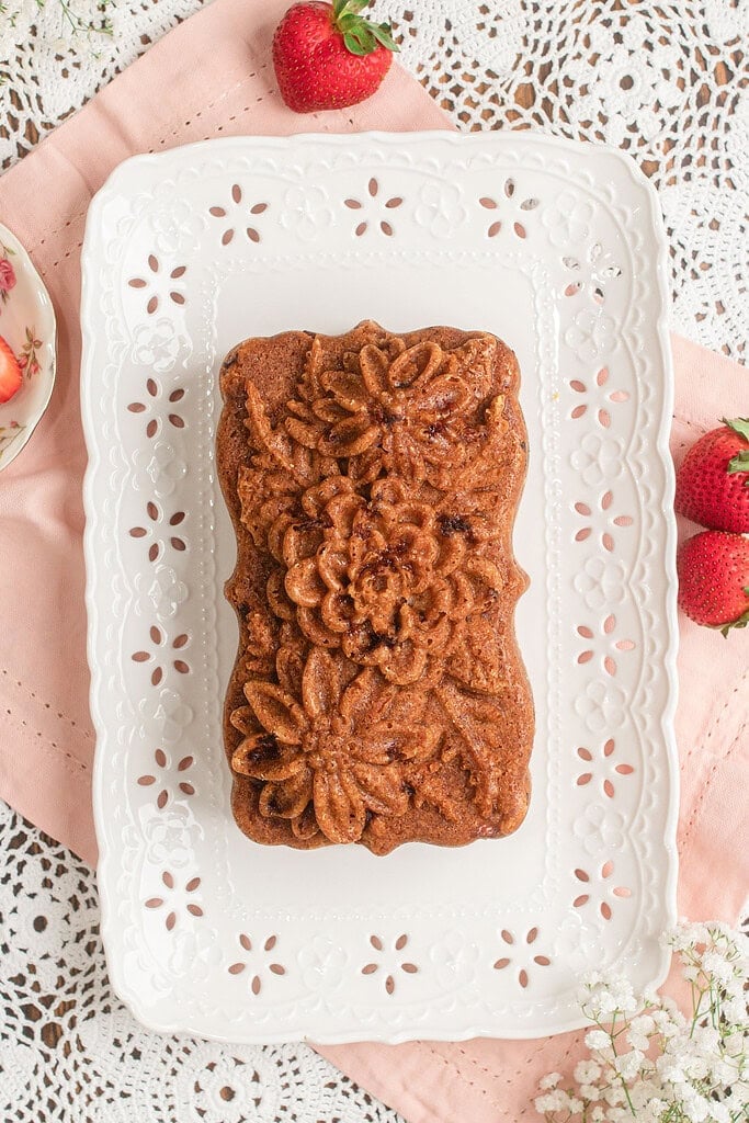Fresh Milled Flour Strawberry Bread turned out of its floral loaf pan onto a white scalloped platter, showing the imprinted floral pattern on the crust
